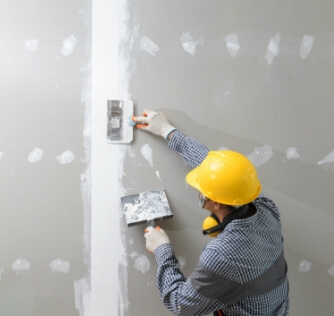 A technician doing drywall work