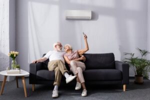 a-couple-adjusting-the-thermostat-of-their-ductless-mini-split-with-a-remote